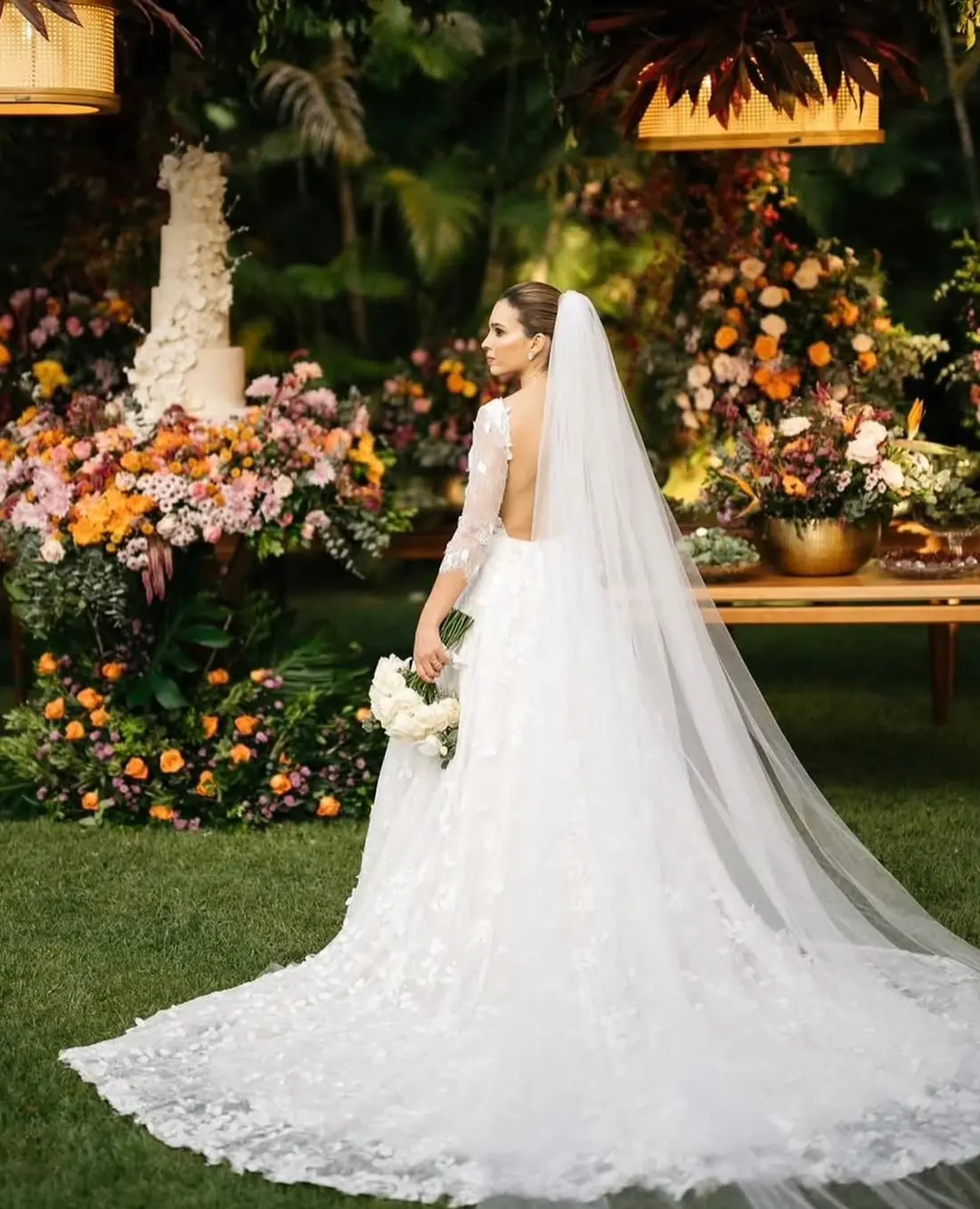 Noiva de costas com véu longo em jardim florido